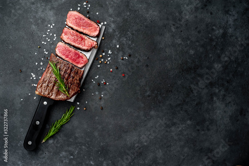 grilled steak over meat knife with spices on a stone background with copy space for your text