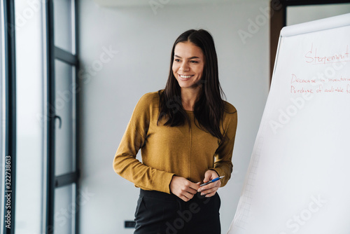 Foto Portrait of businesswoman standing by flipchart while working in office