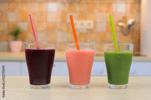 Glass with three smoothie and straw, on the kitchen, close-up