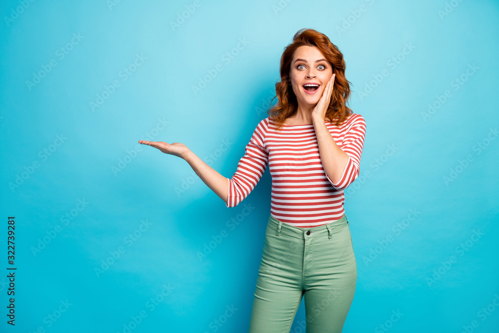 Portrait of funky astonished girl hold hand indicate incredible ads promotion impressed scream wow omg touch hands face wear stylish pullover isolated over blue color background Portrait of funky astonished girl hold hand indicate incredible ads promotion impressed scream wow omg touch hands face wear stylish pullover isolated over blue color background