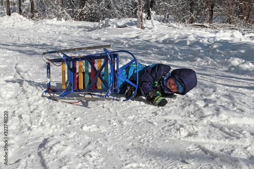 Cuadro en lienzo The boy fell from an overturned sled in the snow