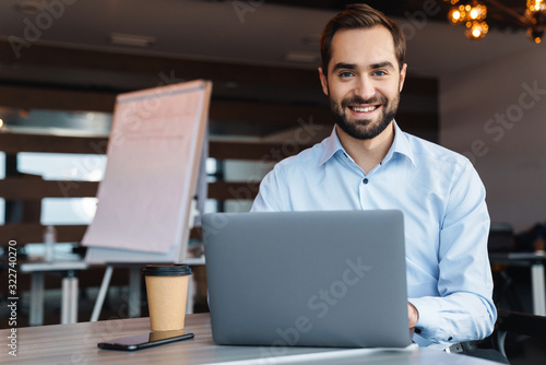 Portrait of young businessman using laptop while working in office