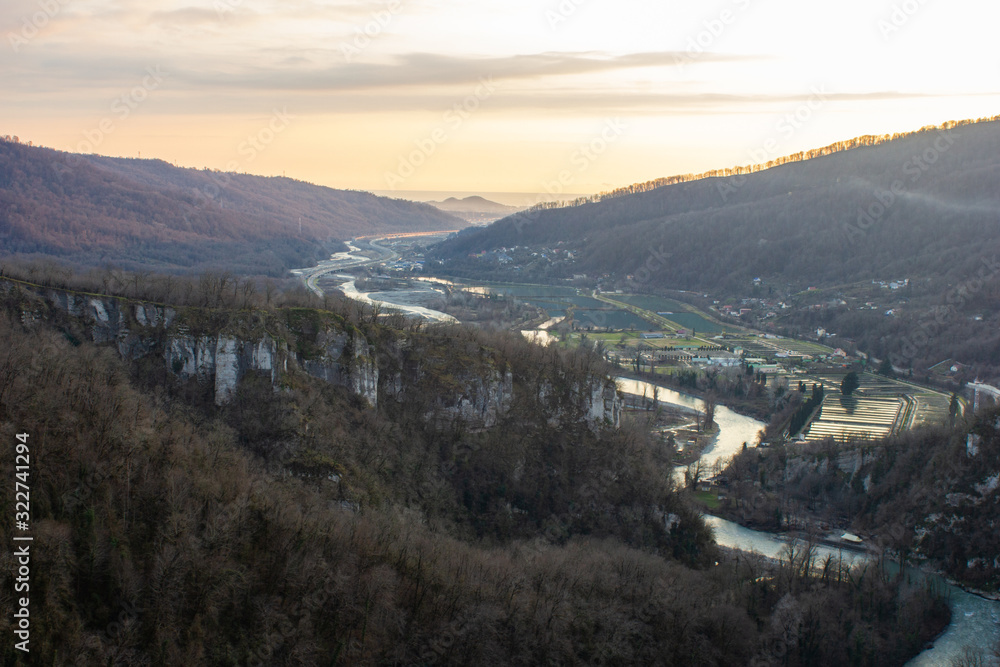 Fototapeta premium View of a mountain valley with a river at sunset. From the longest pedestrian bridge in the world in Sochi