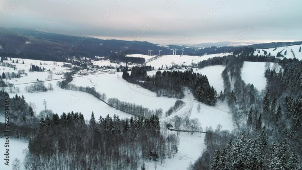 The snow white covered Ramzová village in Czech Republic with windmills in the distance - aerial The snow white covered Ramzová village in Czech Republic with windmills in the distance - aerial