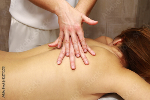 Hands massaging female back.