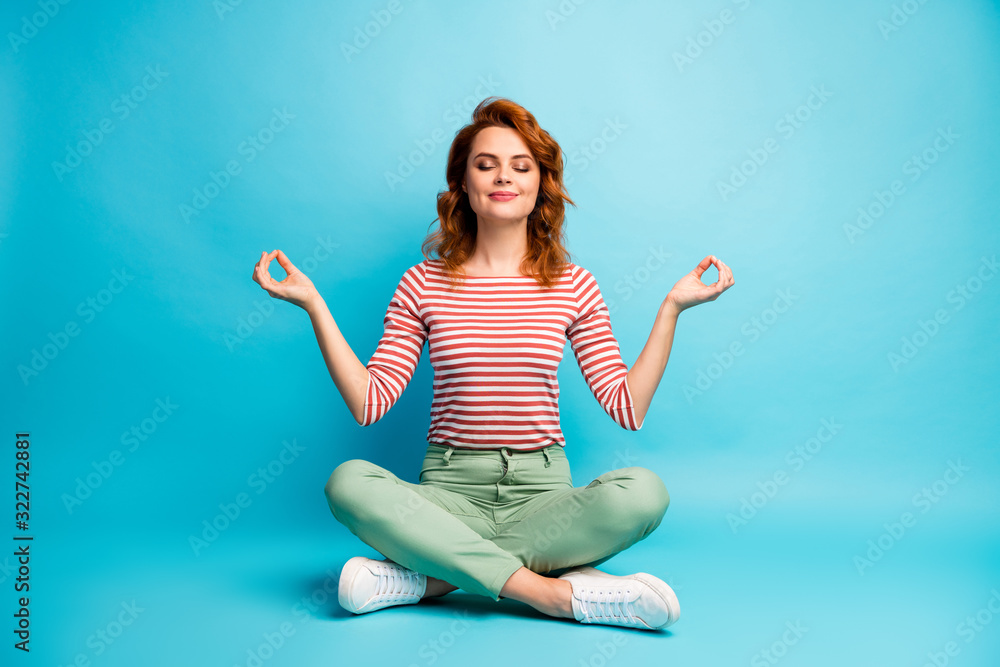 Full size photo of quiet serene woman sit floor crossed legs show om sign exercise yoga meditation wear stylish green outfit isolated over blue color background - obrazy, fototapety, plakaty 
