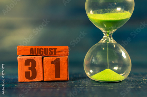 august 31st. Day 31of month,Handmade wood cube with date month and day and hourglass with green sand. Time passing away. artistic coloring.  summer month, day of the year concept photo