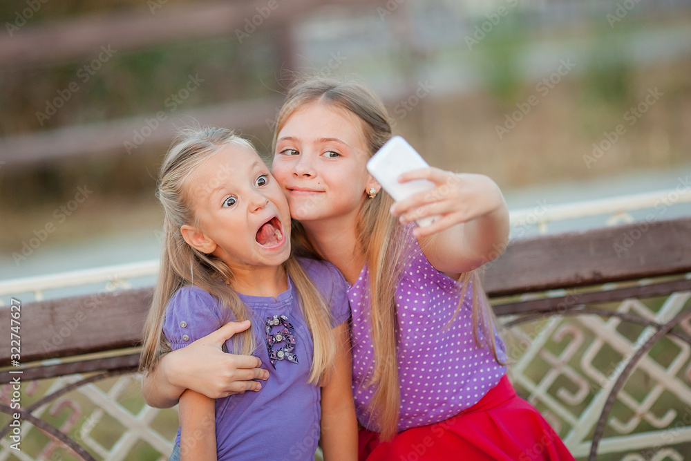 Two joyful girls taking selfie at park.