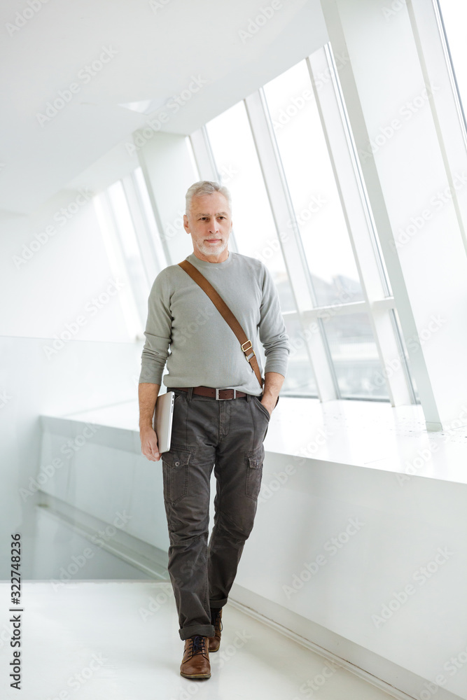 Bearded businessman indoors holding laptop computer. Bearded businessman indoors holding laptop computer.