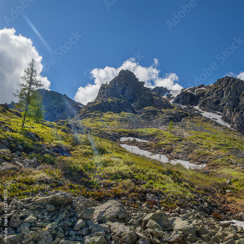 Spring in the mountains. Snow on the mountainside, the first green. Sunny day.