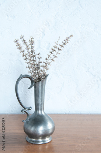 Vintage vase with flowers on a wall background. On wooden background