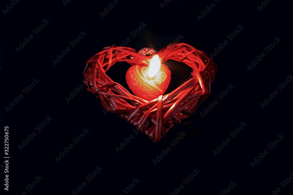 Burning red heart-shaped candle in the dark Burning red heart-shaped candle in the dark