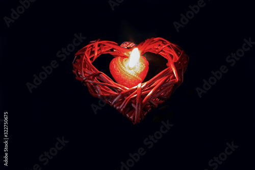 Burning red heart-shaped candle in the dark photo