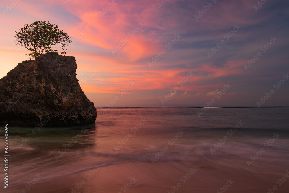 Amazing seascape. Beach during sunset. Rock with tree in the ocean. Slow shutter speed. Bingin beach, Bali