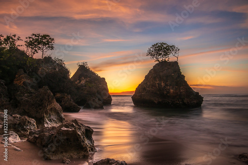 Beautiful seascape. Beach with rocks during sunset. Rock with tree in the ocean. Slow shutter speed. Bingin beach, Bali