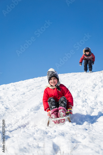 Children have fun sledding on a sunny day