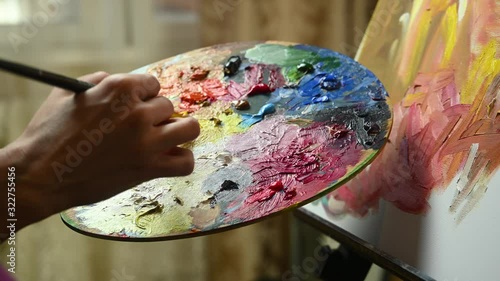artist girl paints on canvas and mix with paint on palette photo