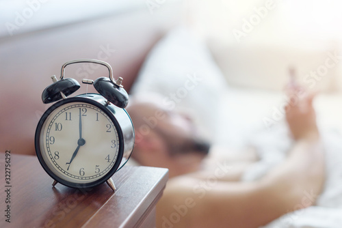 focus on the alarm clock, man wakes up early in the morning, healthy sleep concept, noisy effect for the atmosphere