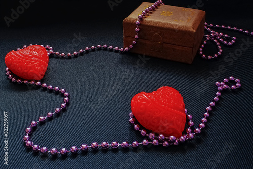 Small hearts with pink beads and a cardboard box for jewelry in the dark