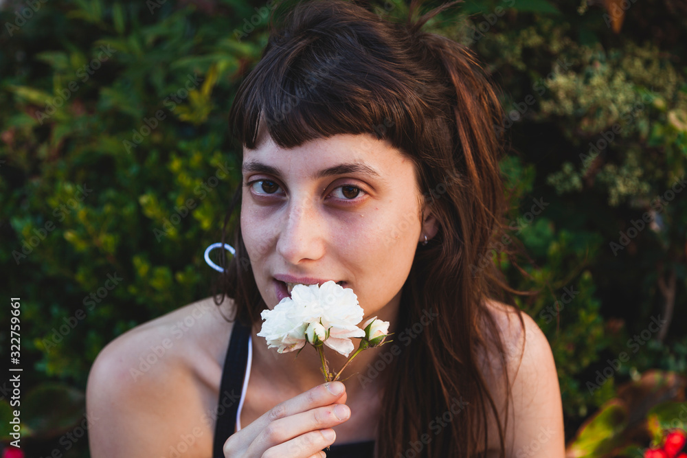 portrait of young cute woman is smelling a white flower portrait of young cute woman is smelling a white flower