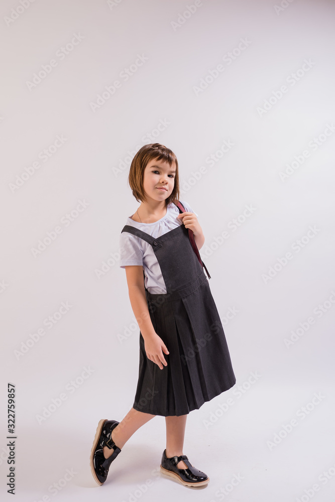 portrait girl of Asian appearance 7 years old schoolgirl in school uniform with backpack on an isolated white background, people concept portrait girl of Asian appearance 7 years old schoolgirl in school uniform with backpack on an isolated white background, people concept