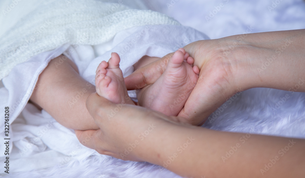 Asian newborn baby holding mother foot on a white cloth,..concept: banner family parents love mother’s day, Healthcare and medical love lifestyle, Closeup Parent childhood little Asian newborn baby holding mother foot on a white cloth,..concept: banner family parents love mother’s day, Healthcare and medical love lifestyle, Closeup Parent childhood little