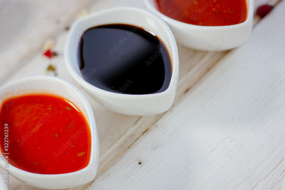 Different dips and sauces - red, white and black over white table. Different dips and sauces - red, white and black over white table.