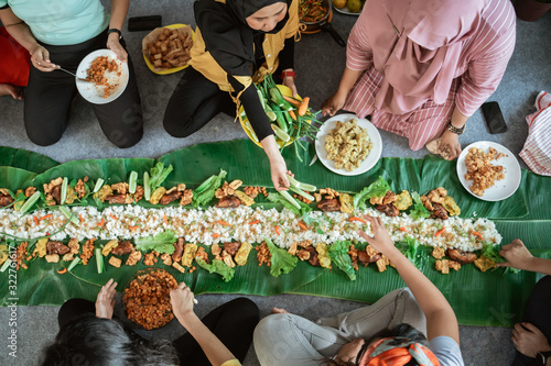 hand gesture preparing javanese traditional food laid on banana leaf on the floor photo
