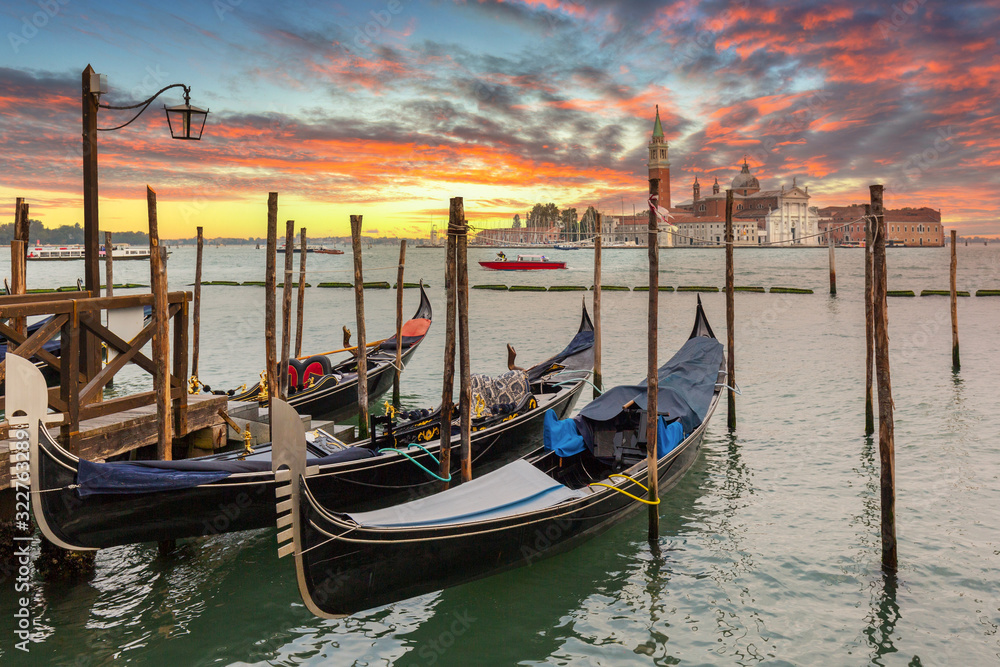Venetian gondolas at the harbor and San Giorgio Maggiore island at sunset, Venice. Italy