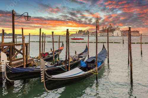 Venetian gondolas at the harbor and San Giorgio Maggiore island at sunset, Venice. Italy