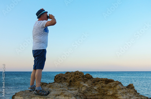 man looks through a telescope at the sea