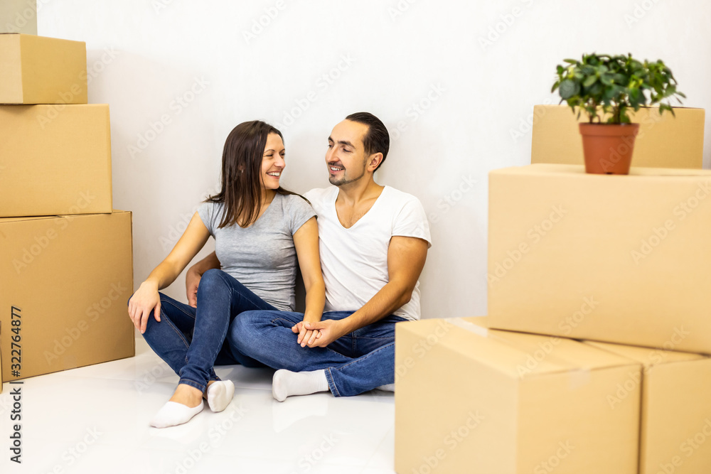Packed and ready to move in new house. Excited young spouses sitting among carton boxes ready to relocate. Packed and ready to move in new house. Excited young spouses sitting among carton boxes ready to relocate.