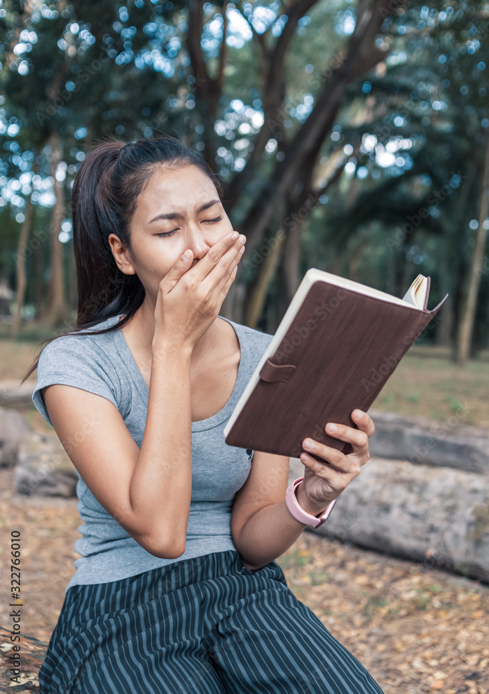 girl tired yawning sit park and read book. girl tired yawning sit park and read book.