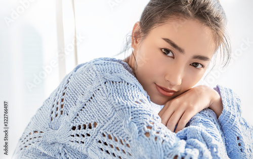 Portrait of young beautiful asian woman relax face in winter bedroom. Closeup sexy beauty fashion girl healthy makeup facial treatment perfect glow skin. Smile happy asia korean girl in blue sweater. photo