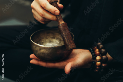 Close-up of hands with rosary playing on singing bowls. Relaxation and meditation. Alternative medicine. Tibetan and Himalayan singing bowls. Make a sound.