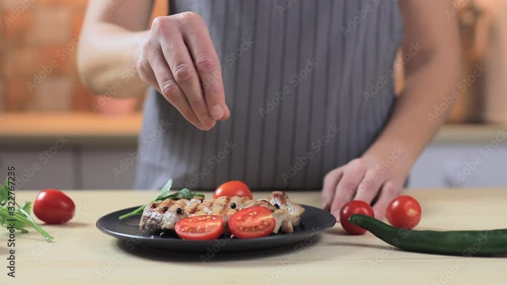 Woman cooking steak on the kitchen - salt it, close-up, slow motion Woman cooking steak on the kitchen - salt it, close-up, slow motion
