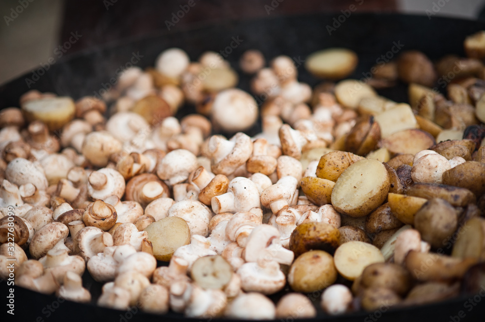 Grilling small potatoes and mushrooms. Street food. Close up of appetizing grilled potatoes and mushrooms on the bbq grill. Grilling small potatoes and mushrooms. Street food. Close up of appetizing grilled potatoes and mushrooms on the bbq grill.