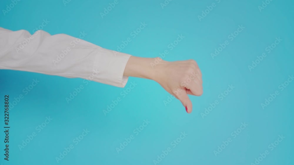 Woman's hand shows finger up, like or dislike, gesture on blue background. Copy space for advertisement. With place for text or image. Advertising area, mock up. Hand doubts the decision Woman's hand shows finger up, like or dislike, gesture on blue background. Copy space for advertisement. With place for text or image. Advertising area, mock up. Hand doubts the decision