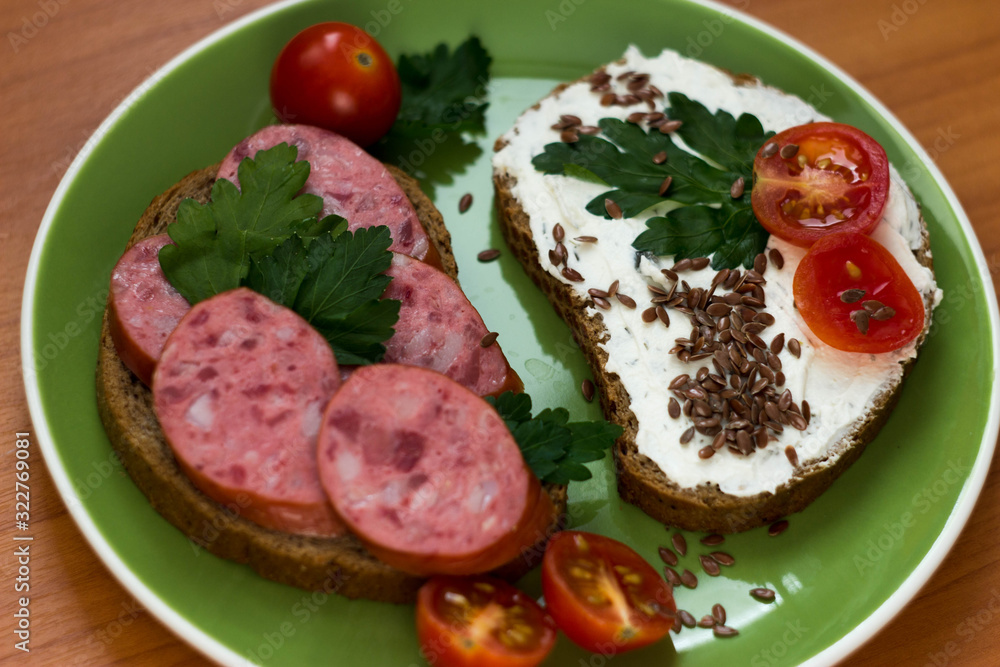 Sausage sandwiches on a plate with tomatoes and herbs Sausage sandwiches on a plate with tomatoes and herbs