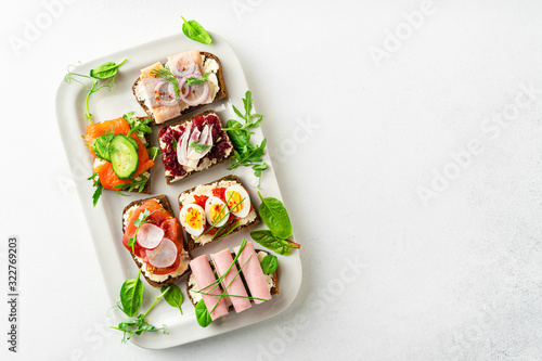 Selection of Danish smorrebrod open sandwiches on a platter on white background, horizontal orientation