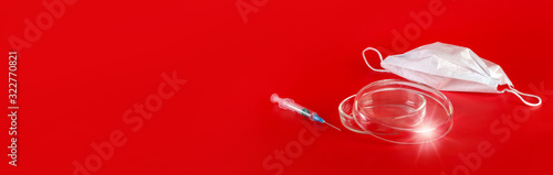 Surgical or viral mask, syringe and laboratory glassware. Red background. Virus epidemic concept, medical concept. Banner