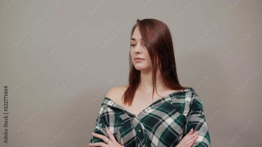 Young brunette girl blue green in checked shirt on grey background happy woman with glasses thinks and holds her chin with her hand Young brunette girl blue green in checked shirt on grey background happy woman with glasses thinks and holds her chin with her hand