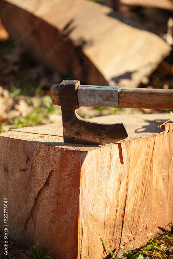 An ax embedded in an old stump chopping block in outdoor nature An ax embedded in an old stump chopping block in outdoor nature