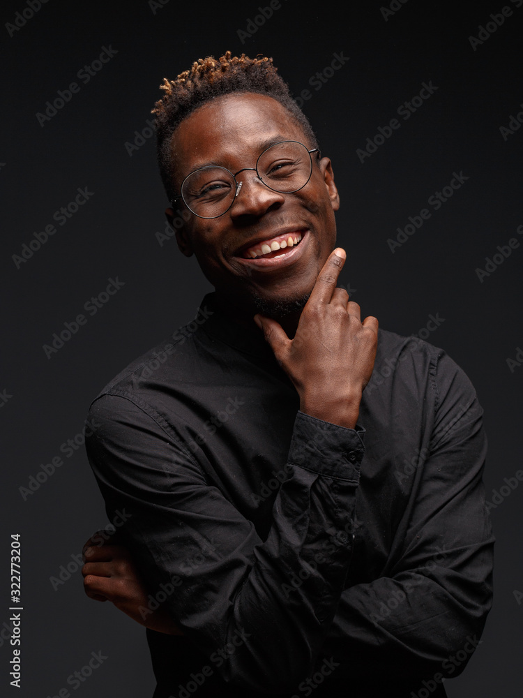 Emotional portrait of a young African man in black clothing against a dark background. Studio photography. Emotional portrait of a young African man in black clothing against a dark background. Studio photography.