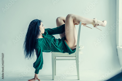 Semi-nude beautiful girl posing on a chair in a classic suit