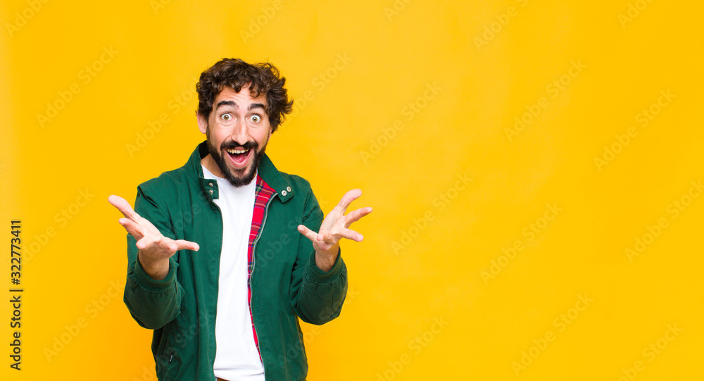 young crazy bearded man feeling happy, astonished, lucky and surprised, like saying omg seriously? Unbelievable against flat wall - obrazy, fototapety, plakaty 