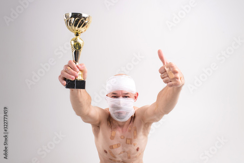 Picture of sufferer male with bandaged head holds a gold cup