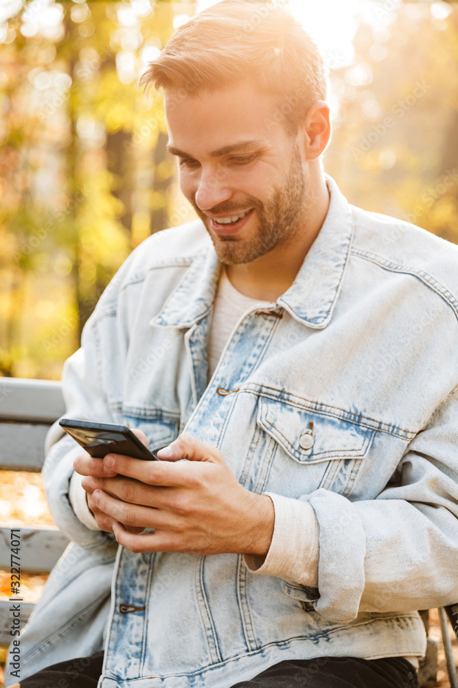 Handsome young man sitting on a bench in the autumn park Handsome young man sitting on a bench in the autumn park