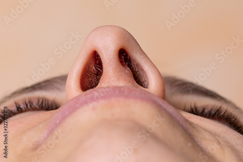 Nose of a woman seen from below. Laser hair removal concept of nose hair photo