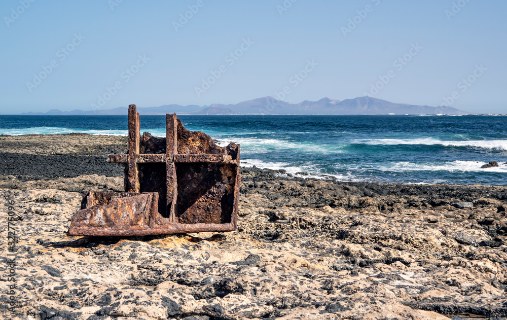Piece of rusty boat on a shore of Fuerteventura Island. On the horizon is Lanzarote Island